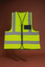 Yellow safety vest with reflective stripes on a brown background